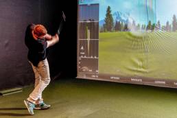 En mann spiller golf på golfsimulator